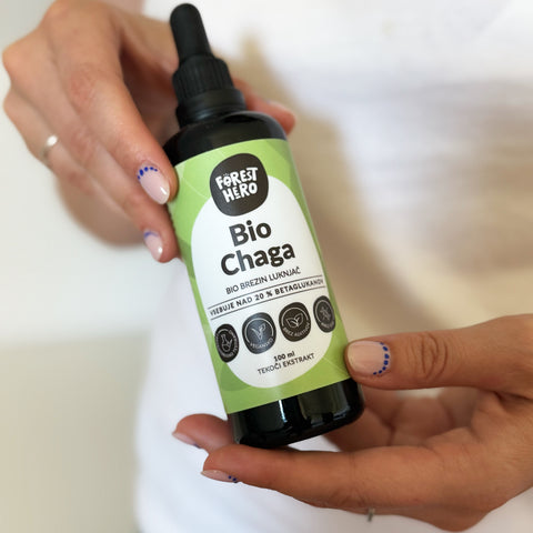 Hand holding a bottle labeled 'Bio Chaga' by Forest Hero on a blurred background